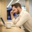 Man sitting with back pain at a laptop.